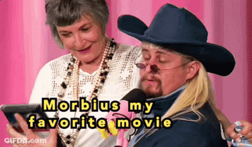 A Man In A Cowboy Hat Is Talking Into A Microphone While A Woman Watches GIF
