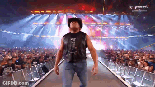 A Man In A Cowboy Hat Is Walking Down A Ramp In Front Of A Crowd With Peacock In The Background GIF