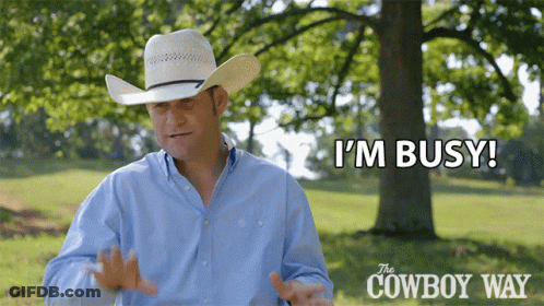 A Man In A Cowboy Hat Says " I 'M Busy " In Front Of A Tree GIF