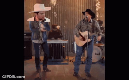 A Man In A Cowboy Hat Sings Into A Microphone GIF
