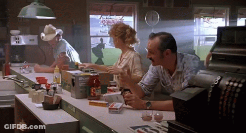 A Man In A Cowboy Hat Sits At A Counter In A Diner Talking To A Woman And Another Man GIF