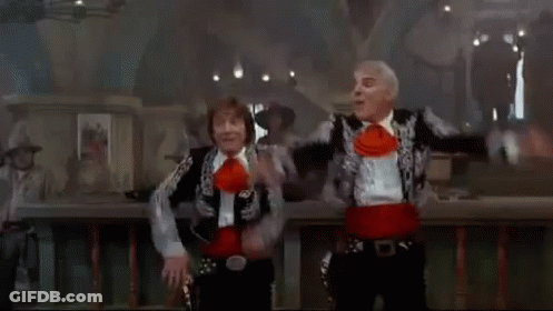 A Man In A Cowboy Hat Sits In A Chair In Front Of A Group Of People Dancing GIF