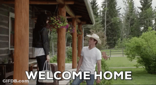 A Man In A Cowboy Hat Stands On A Porch With A Woman Holding A Bag And The Words Welcome Home Above Him GIF
