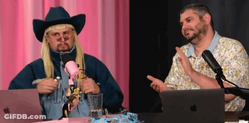 A Man In A Cowboy Hat Talks Into A Microphone While Another Man Looks On GIF