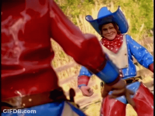 A Man In A Cowboy Outfit Is Holding A Gun GIF
