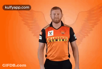 A Man In A Cricket Jersey Is Holding A Bat In His Hand . GIF