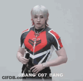 A Man In A Crop Top Is Holding A Microphone In His Hand . GIF