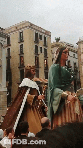 A Man In A Crown Stands Next To A Woman In A Dress GIF