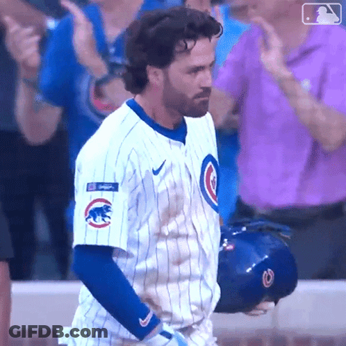 A Man In A Cubs Uniform Is Standing In Front Of A Crowd Applauding GIF