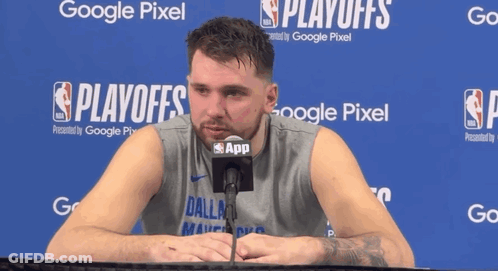 A Man In A Dallas Shirt Is Talking Into A Microphone In Front Of A Google Pixel Sign GIF