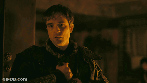 A Man In A Dark Room Holds A Sword In His Hand GIF
