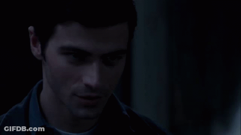 A Man In A Dark Room Is Holding His Finger To His Lips GIF