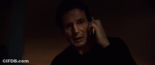 A Man In A Dark Room Is Talking On A Cell Phone . GIF