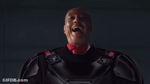 A Man In A Dark Room With A Light Coming Out Of The Ceiling GIF