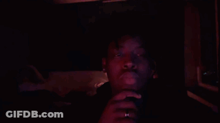A Man In A Dark Room With A Red Light Shining On His Face GIF