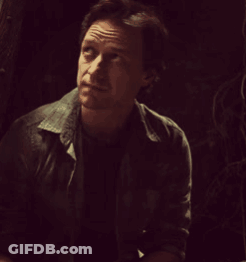 A Man In A Dark Room With His Eyes Closed And A Serious Look On His Face GIF