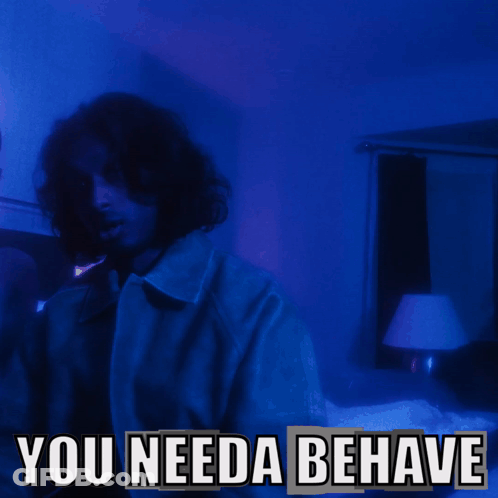 A Man In A Dark Room With The Words " You Needa Behave " Below Him GIF