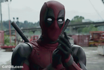 A Man In A Deadpool Costume Is Holding A Gun In His Hand . GIF