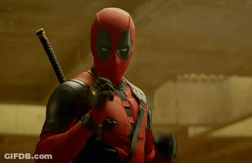 A Man In A Deadpool Costume Is Holding A Sword And Giving The Peace Sign GIF