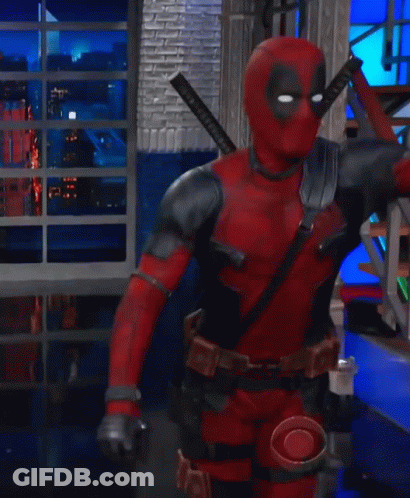 A Man In A Deadpool Costume Is Kneeling Down In A Room With Stairs GIF