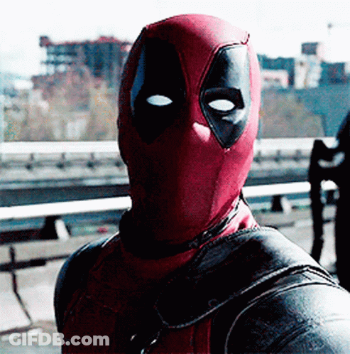 A Man In A Deadpool Costume Is Standing In Front Of A Bridge GIF