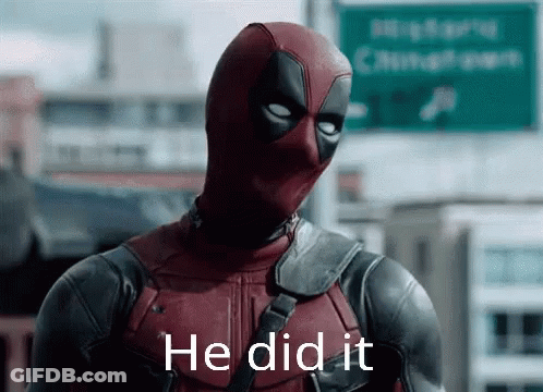 A Man In A Deadpool Costume Is Standing In Front Of A Green Sign . GIF