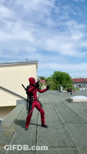 A Man In A Deadpool Costume Is Standing On A Rooftop GIF