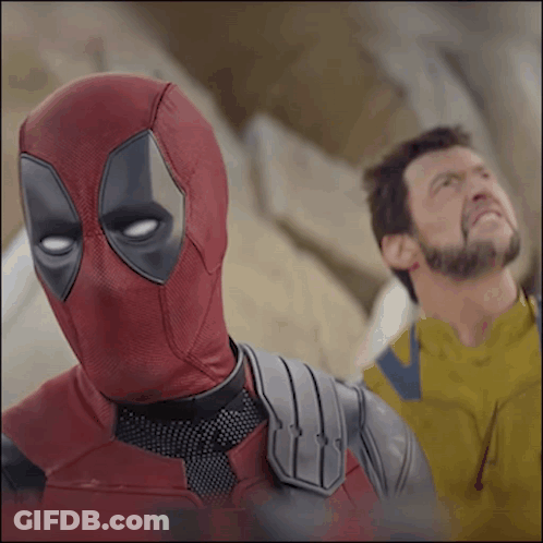 A Man In A Deadpool Costume Stands Next To A Man In A Yellow Jacket GIF