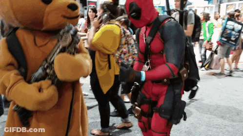 A Man In A Deadpool Costume Stands Next To A Teddy Bear GIF