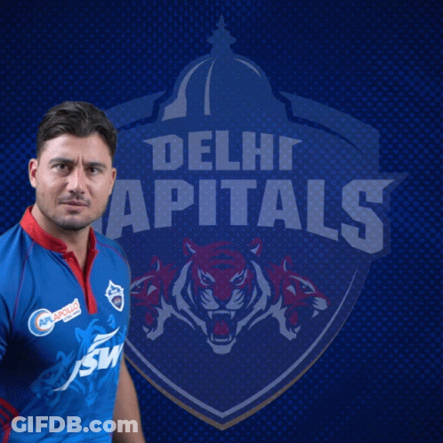 A Man In A Delhi Capitals Jersey Stands In Front Of The Team Logo GIF