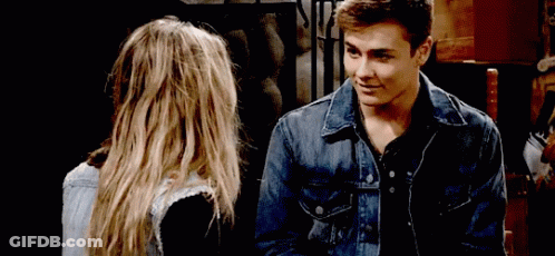 A Man In A Denim Jacket Is Looking At A Woman GIF