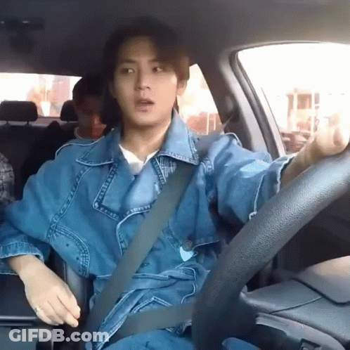 A Man In A Denim Jacket Is Sitting In A Car With A Seat Belt On . GIF