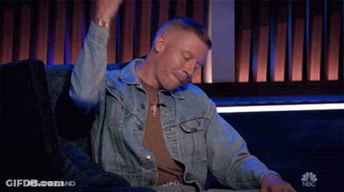 A Man In A Denim Jacket Is Sitting On A Couch With His Arms In The Air And The Words Songland On The Bottom Right GIF