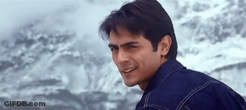 A Man In A Denim Jacket Is Smiling And Looking At The Camera . GIF