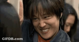 A Man In A Denim Jacket Is Smiling And Making A Funny Face In A Crowd Of People . GIF