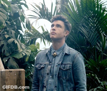 A Man In A Denim Jacket Is Standing In A Jungle GIF