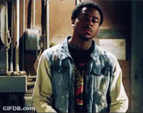 A Man In A Denim Jacket Is Standing In A Room GIF