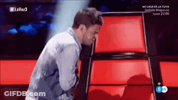 A Man In A Denim Jacket Is Standing In Front Of A Red Wall On A Television Show . GIF