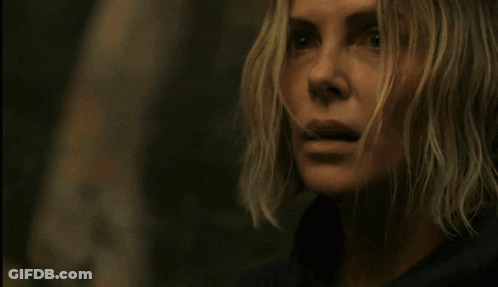 A Man In A Denim Jacket Is Standing In The Woods With Trees In The Background GIF