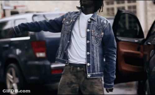 A Man In A Denim Jacket Is Standing Next To A Black Suv GIF