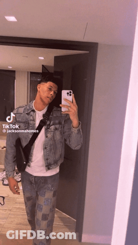 A Man In A Denim Jacket Is Taking A Picture Of Himself In A Mirror .. GIF