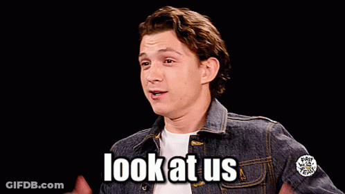 A Man In A Denim Jacket Says Look At Us With His Hands In The Air GIF