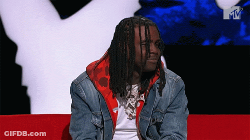 A Man In A Denim Jacket Sits On A Red Couch GIF