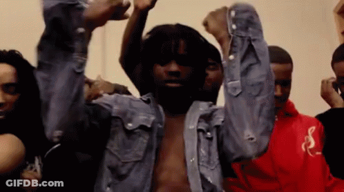 A Man In A Denim Shirt Is Dancing With His Arms In The Air . GIF