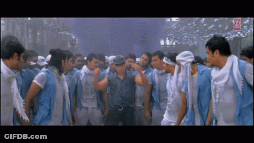 A Man In A Denim Shirt Is Standing In A Crowd Of Men GIF