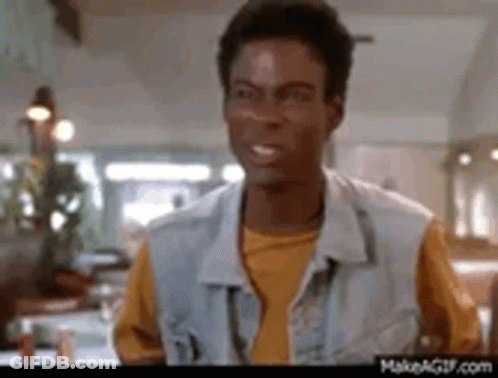 A Man In A Denim Vest And Yellow Shirt Is Standing In A Kitchen . GIF