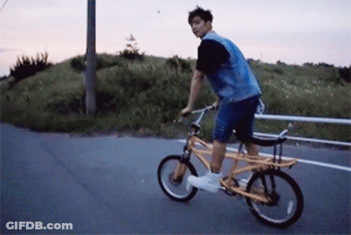 A Man In A Denim Vest Is Riding A Yellow Bike GIF