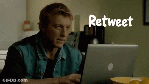 A Man In A Denim Vest Is Using A Laptop With The Word Retweet Above Him GIF