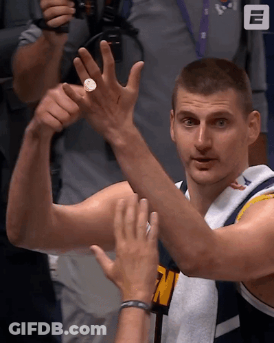 A Man In A Denver Jersey Holds Up A Coin GIF