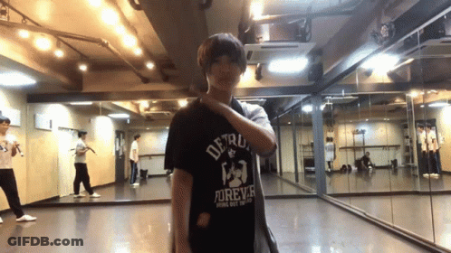 A Man In A Detroit Forever Shirt Is Standing In Front Of A Mirror GIF